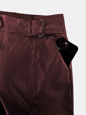 Burgundy faux leather palazzo trousers with belted waist and pocket detail.