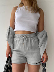 Light Gray textured gauze shorts with drawstring waist and matching button-up shirt draped on shoulders.
