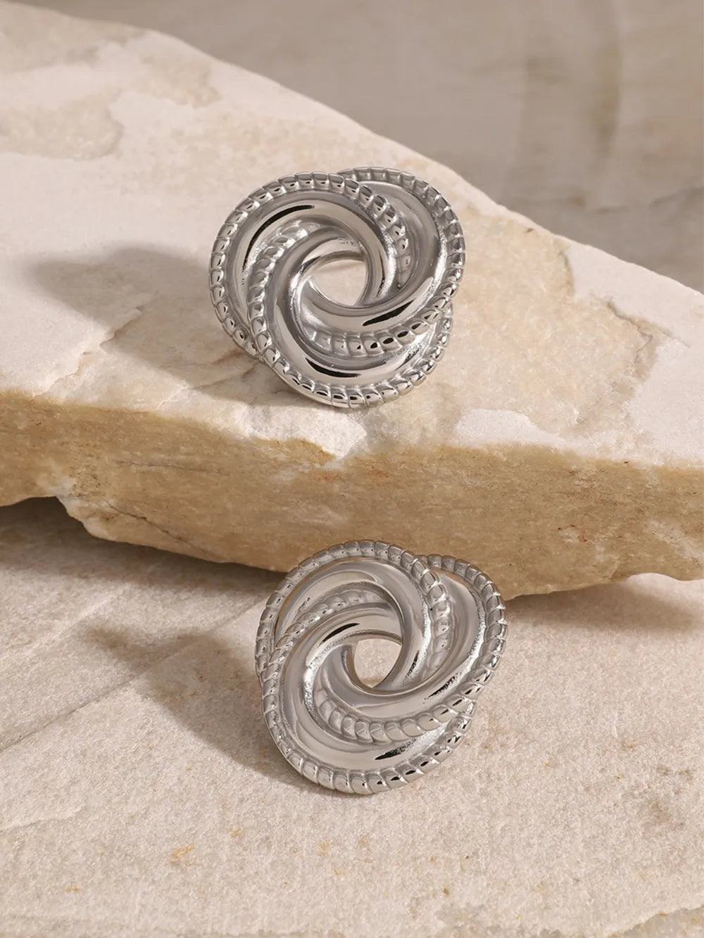 Silver swirl knot stud earrings with textured rope edge detail