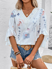 White floral bell sleeve blouse with lace V-neck detail and ruffled cuffs.