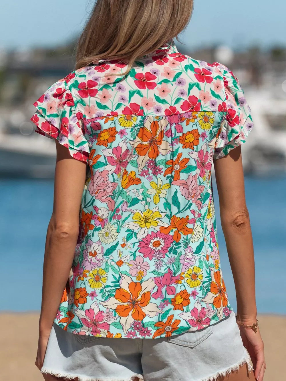Vibrant floral print maternity overshirt with flutter sleeves and a buttoned front.