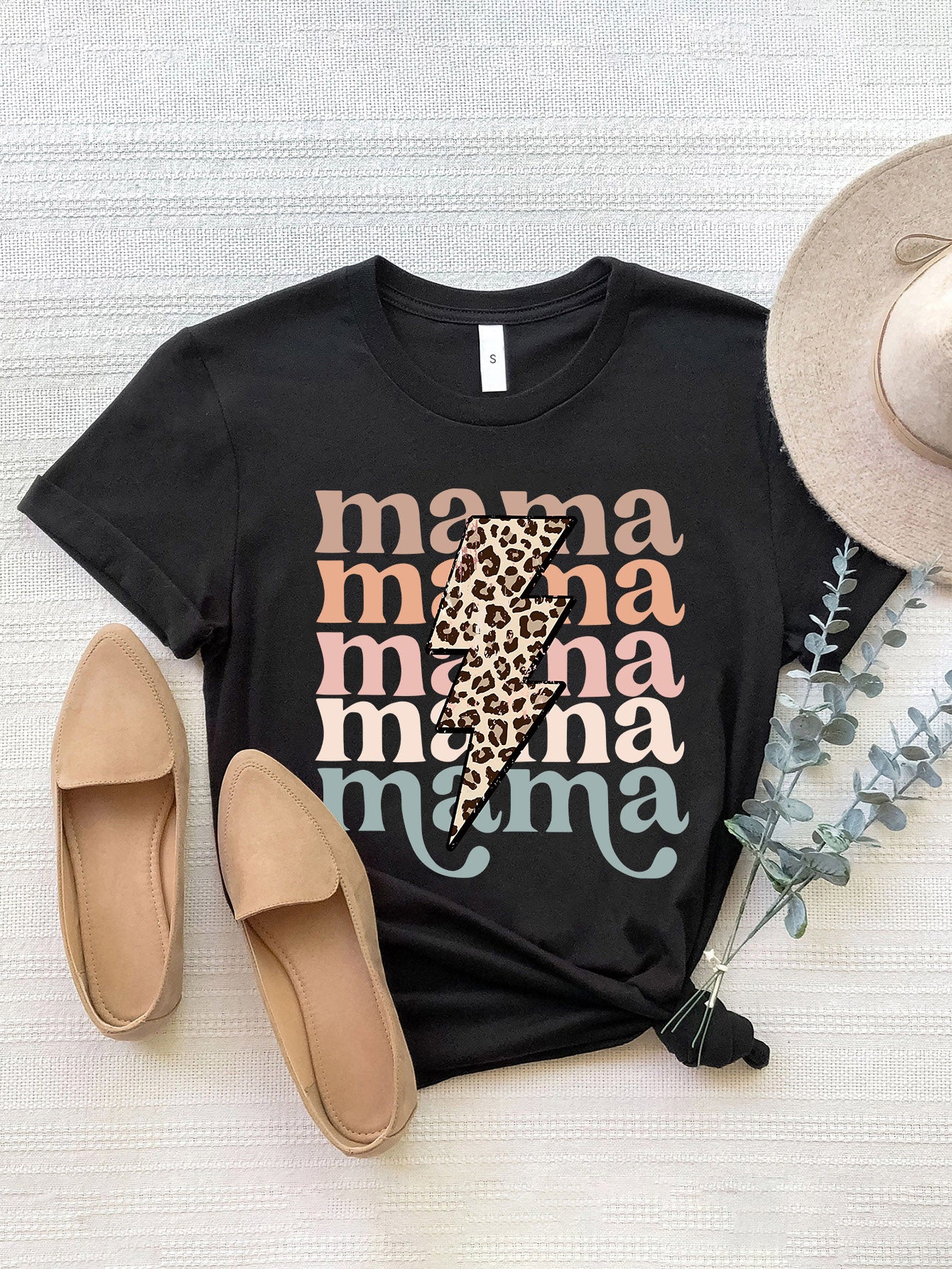 Black graphic t-shirt with "Mama" text in pastel colors and a leopard print lightning bolt.