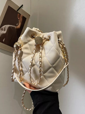 Chic quilted bucket crossbody bag in white with gold chain detail.