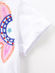 White cotton baby dress with colorful sequin rainbow and floral embroidery detail.