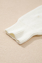 Ivory knit sweater sleeve detail with ribbed cuff and textured knit fabric.