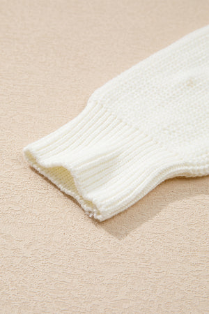 Ivory knit sweater sleeve detail with ribbed cuff and textured knit fabric.
