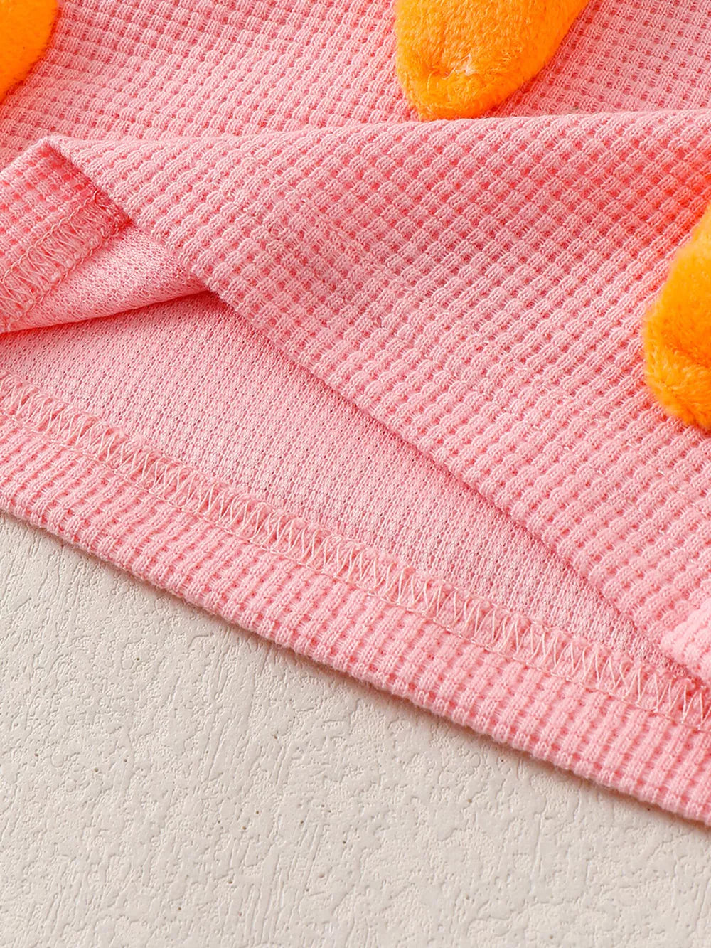 Pink waffle knit baby set with 3D carrot appliqués.