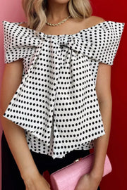 Chic off-shoulder polka dot blouse with a large bow detail and draped front.