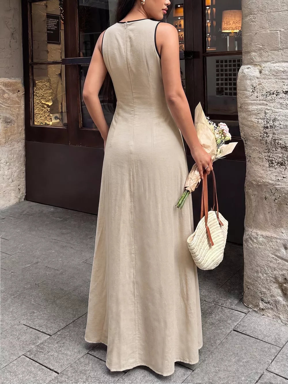 Elegant beige maxi dress with black piping details and a flowing skirt.