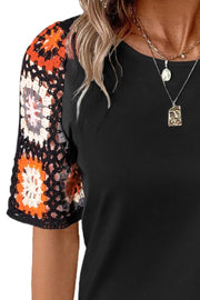 Black t-shirt with colorful granny square crochet sleeves.