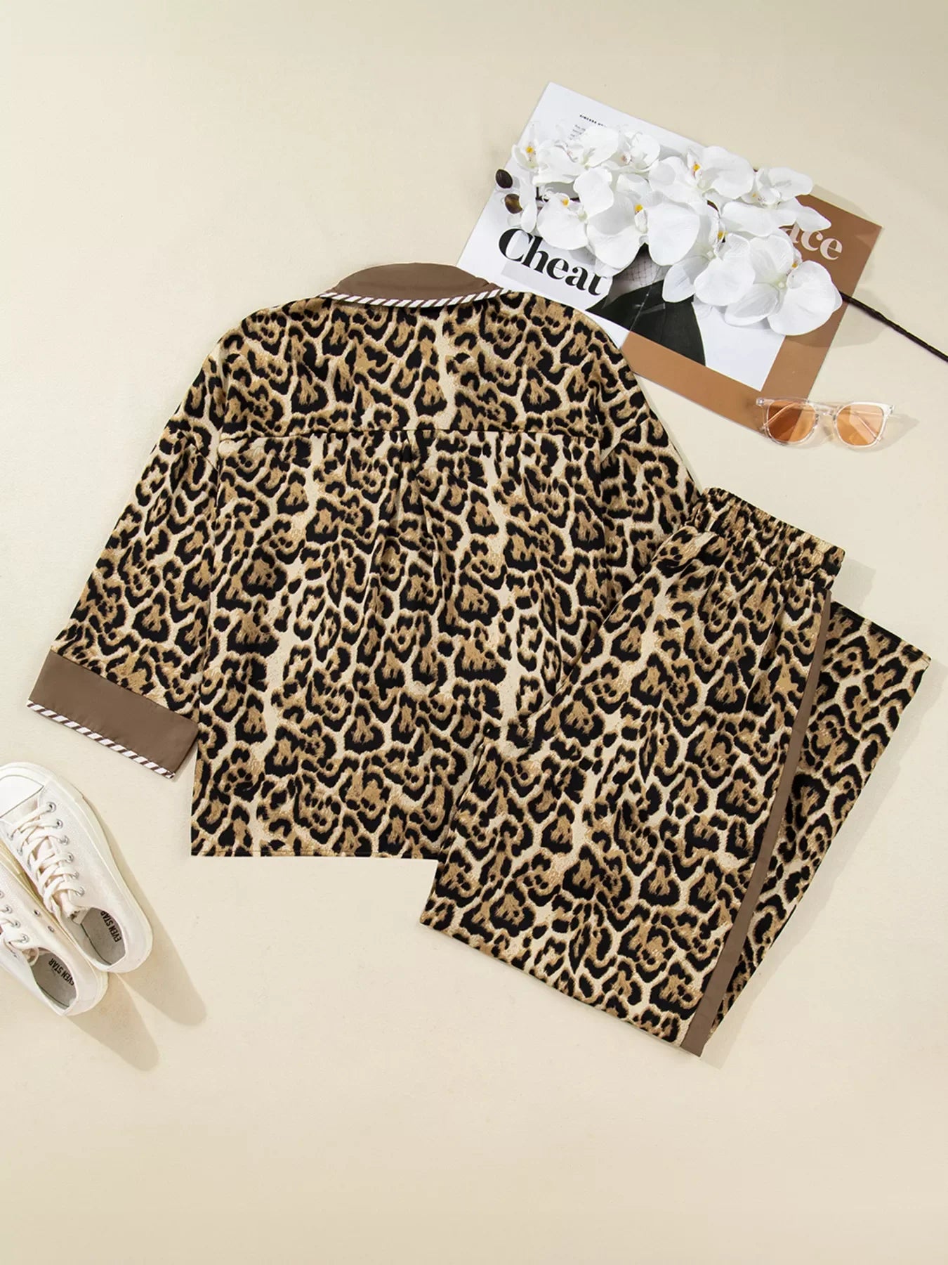 Leopard print two-piece set with buttoned shirt and pants, featuring brown trim.