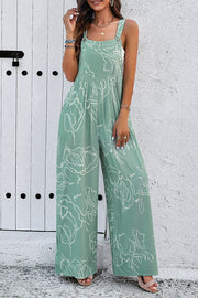 Light green wide leg jumpsuit with abstract floral print and button straps.