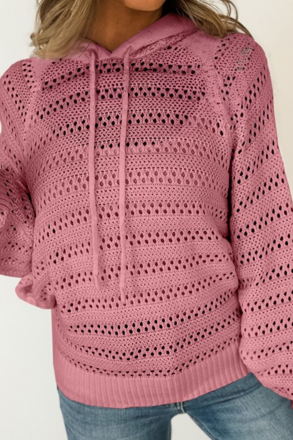 Dusty pink openwork knit hoodie with drawstring and cotton blend material.