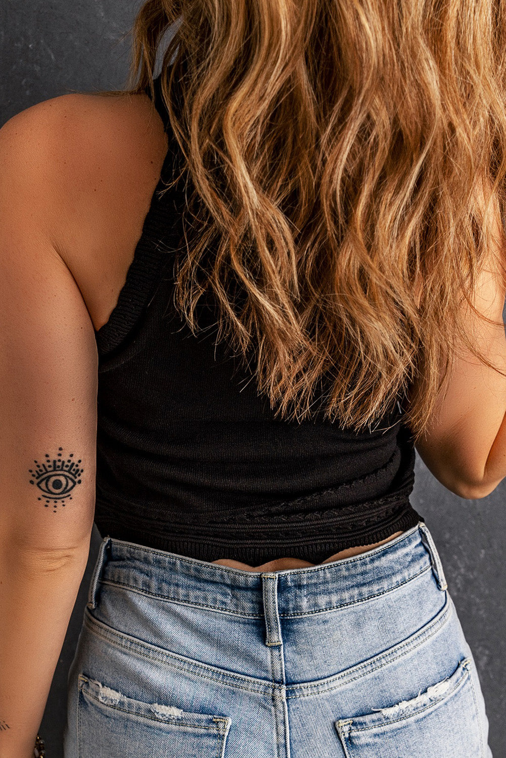 Black scalloped knit halter top with eye tattoo detail on arm