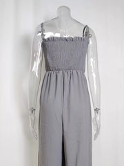 Gray smocked wide leg romper with adjustable spaghetti straps and wide legs.