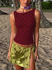 Wine red polka dot tank top with boat neck, styled with a sequined green mini skirt.