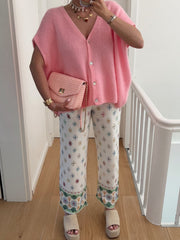 Pink mohair cap sleeve cardigan with pearl buttons, styled with patterned pants and a pink woven crossbody bag.