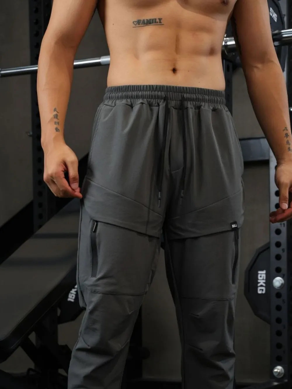 Gray technical joggers with zip pockets and drawstring waist.