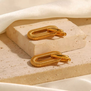 Gold sculptural link drop earrings with ribbed texture and polished finish.