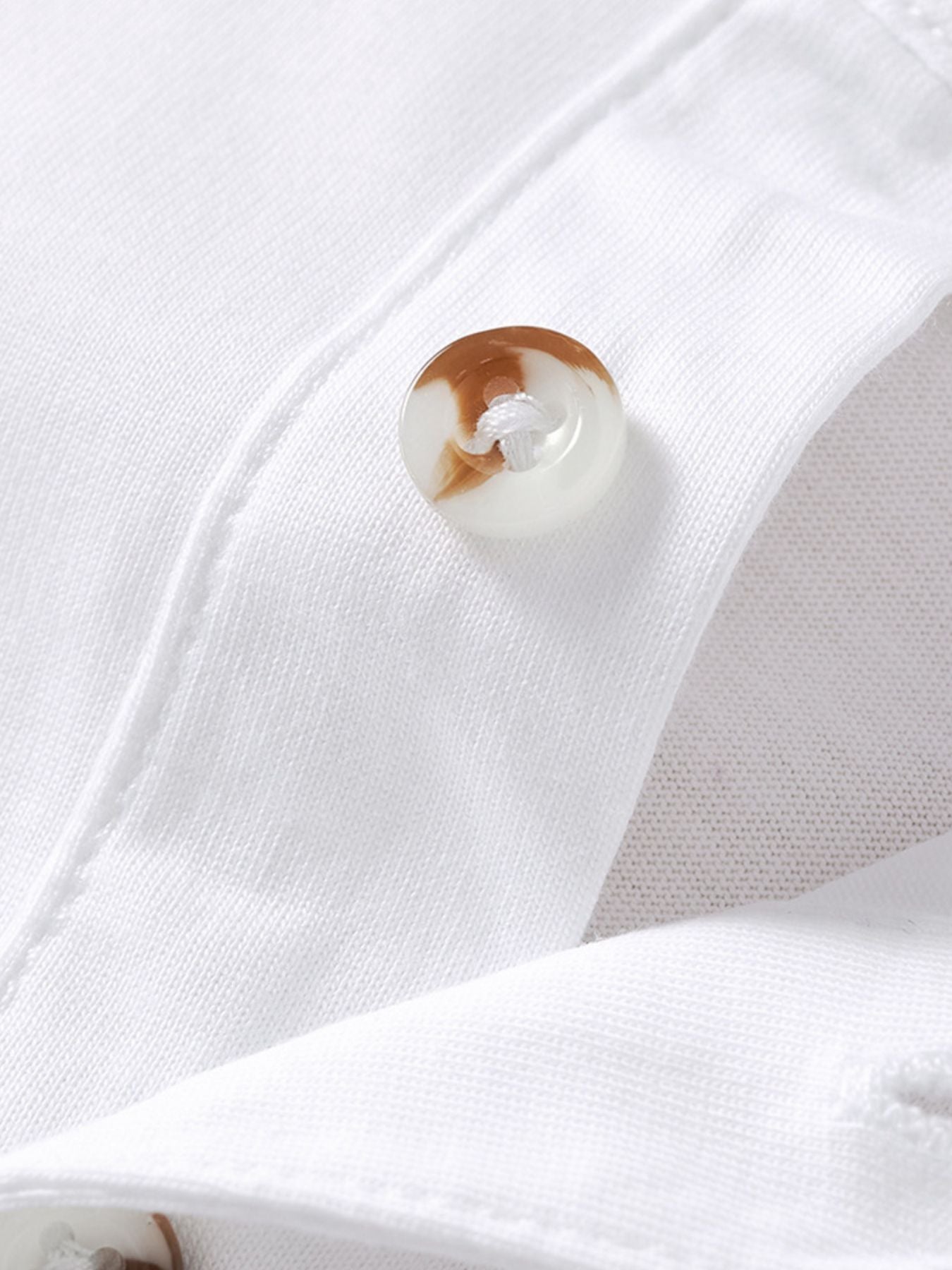 White cotton polo shirt with button detail and chest pocket.