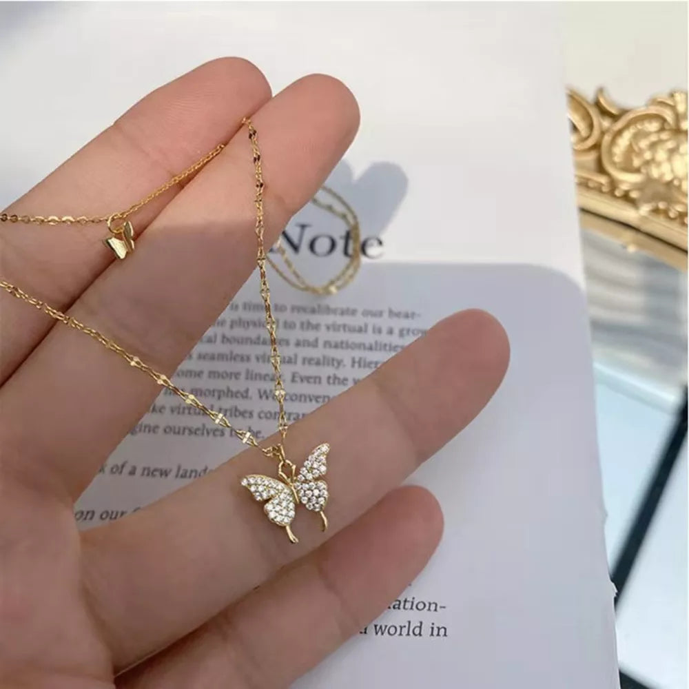 Gold double-layer necklace with a sparkling butterfly charm and a smaller butterfly charm.