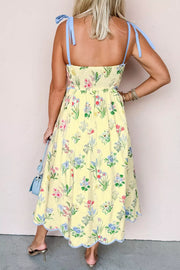 Floral midi dress with bow straps, smocked bodice, and scalloped hem.