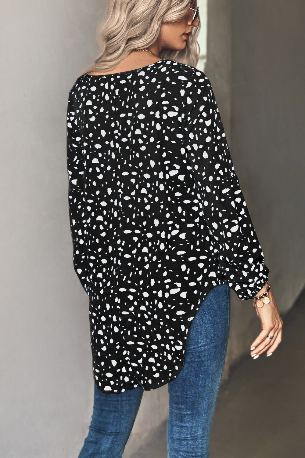 Black dalmatian print blouse with balloon sleeves and a curved hem.