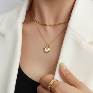 Gold layered necklace with a textured heart locket pendant.