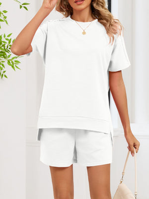 White relaxed two-piece set with crew neck t-shirt and shorts, featuring pockets and side slits.