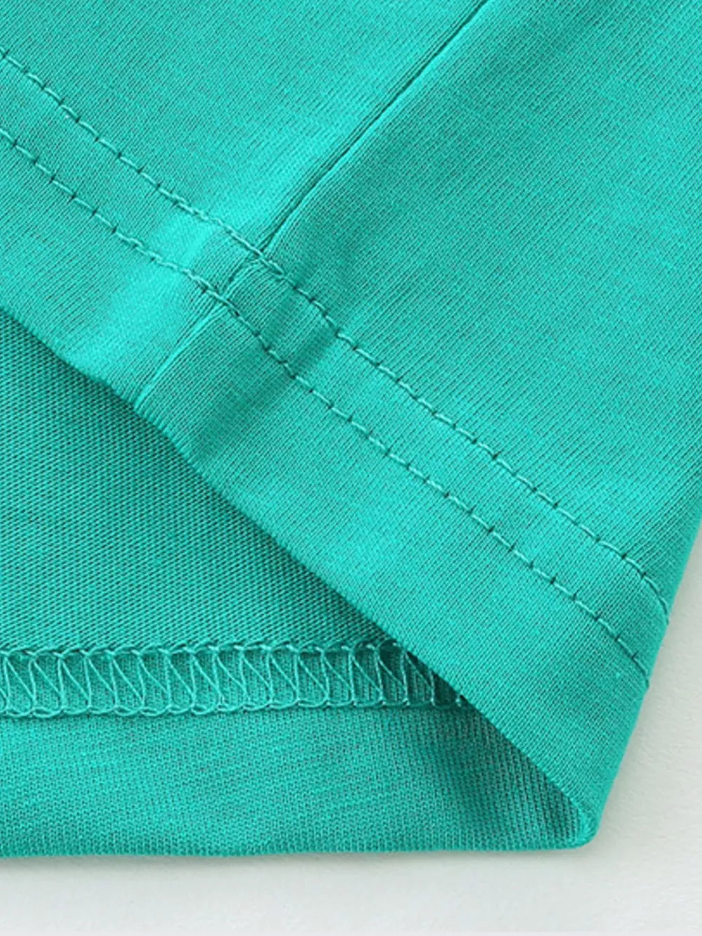 Teal t-shirt detail showing hem and seam stitching.