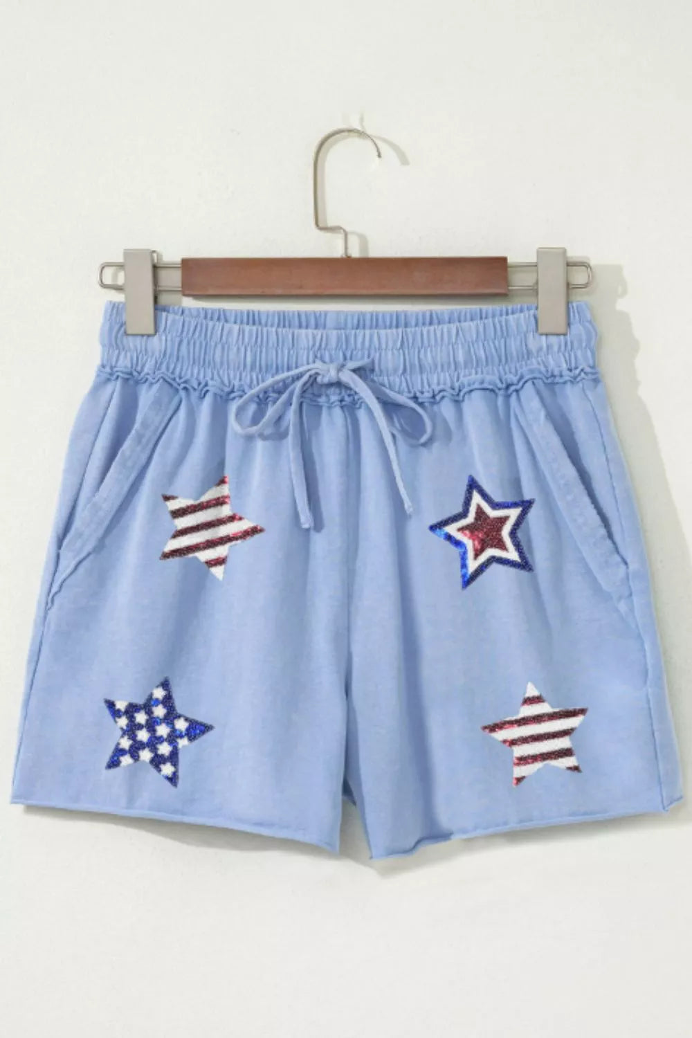 Light blue cotton chino shorts with drawstring and sequined stars pattern.