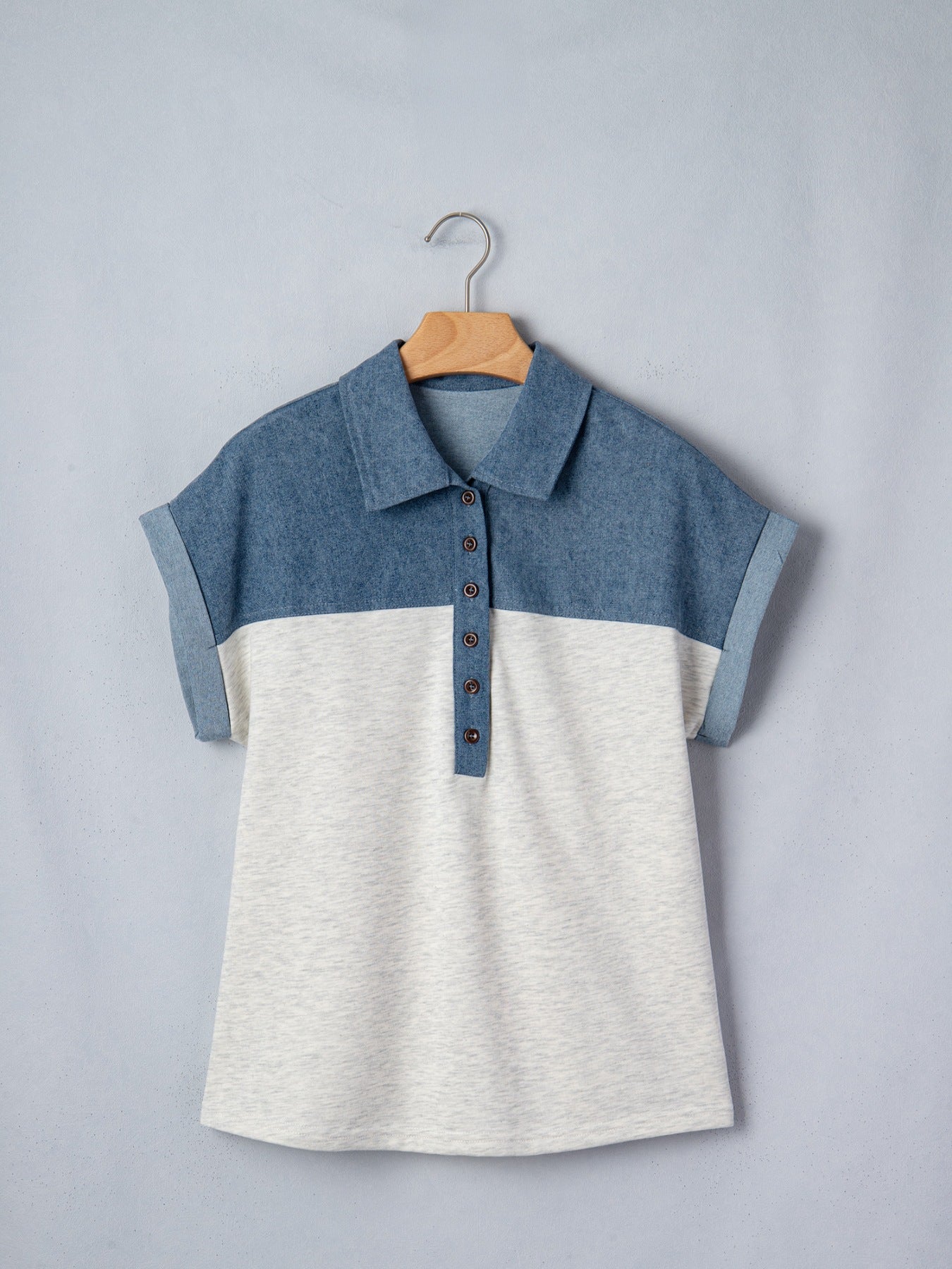 Two-tone denim polo shirt with button placket and rolled sleeves.