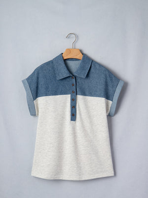 Two-tone denim polo shirt with button placket and rolled sleeves.