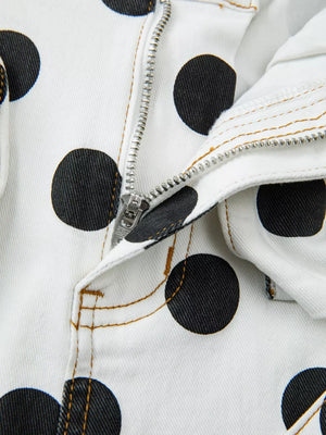 White denim jeans with black polka dots and a silver zipper detail.