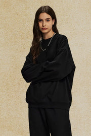 Black oversized crewneck sweatshirt with subtle shoulders and a relaxed fit.