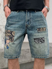 Men's blue denim shorts with graphic patchwork details and a distressed finish.
