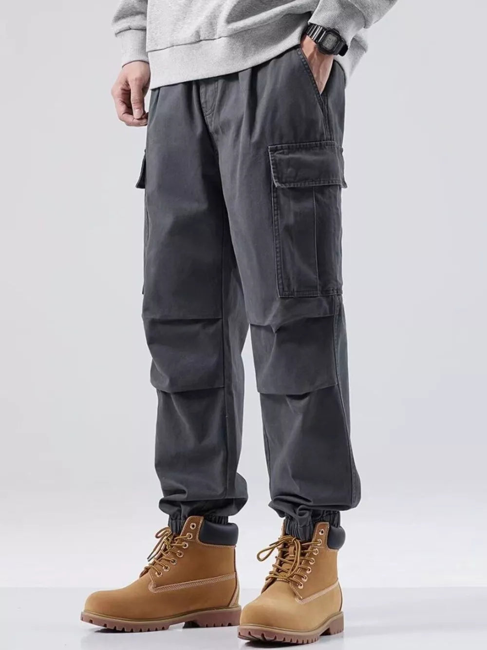 Plus-size dark gray relaxed fit cargo sweatpants with multiple pockets and cuffed ankles.
