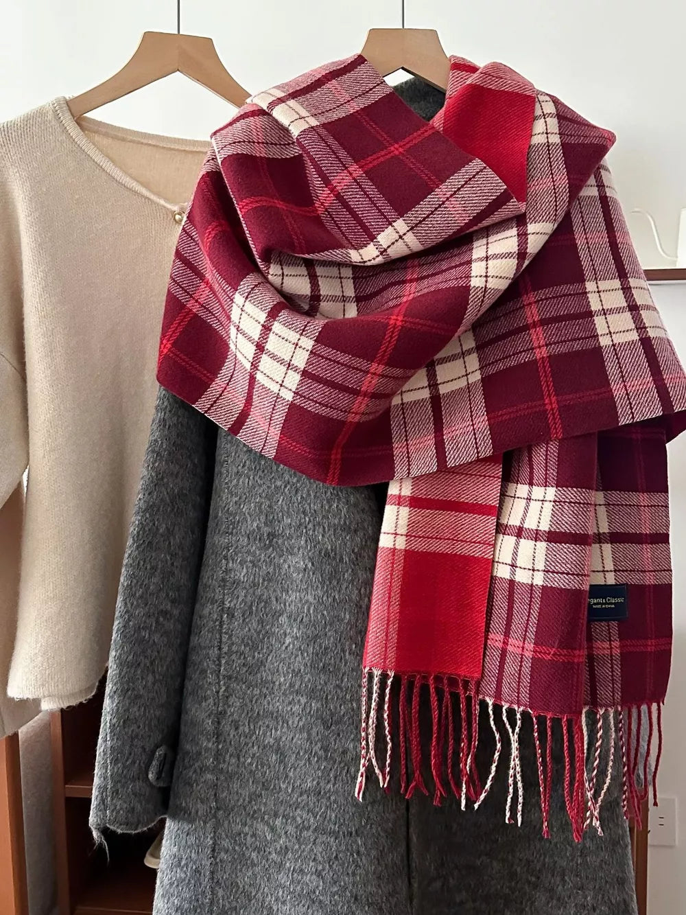 Red plaid fringe scarf with cream and white accents, a classic cozy accessory.