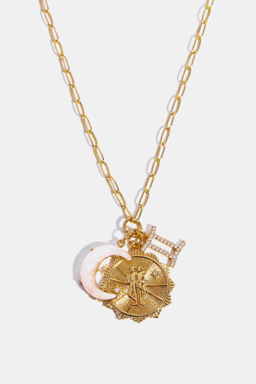 Gold celestial pendant necklace with Gemini symbol, moon charm, and sun medallion.