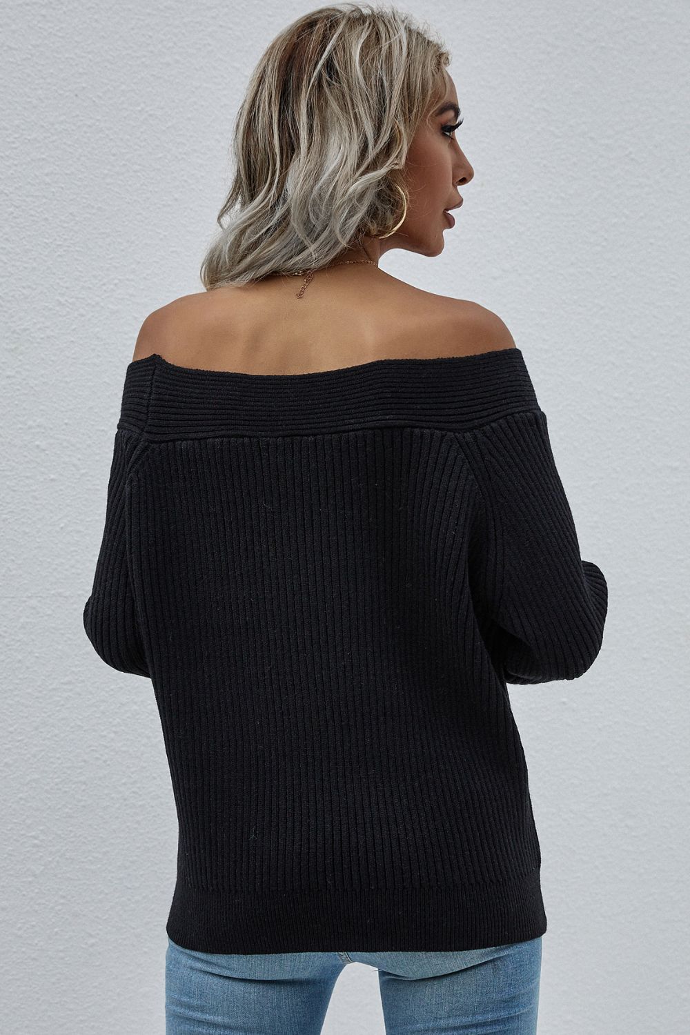 Black ribbed knit sweater with off-the-shoulder neckline and long sleeves.