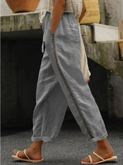 Grey relaxed cropped pants with hollow out trim detail and drawstring waist.
