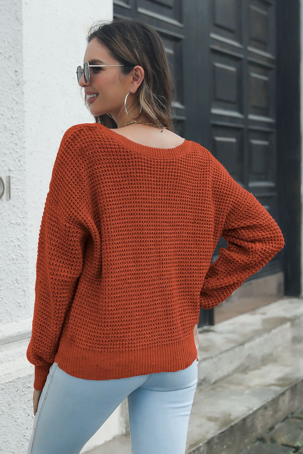 Rust waffle knit sweater with a relaxed fit and crew neck, styled with light wash jeans.