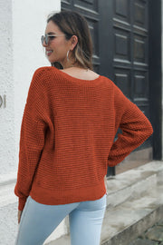 Rust waffle knit sweater with a relaxed fit and crew neck, styled with light wash jeans.