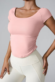 Blush pink performance tee with gathered side detail and scoop neck.