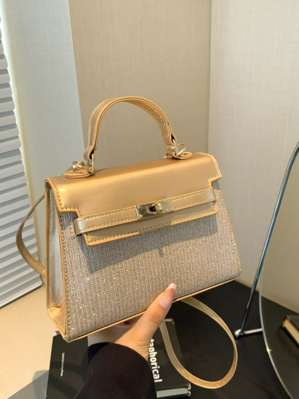 Gold glitter textured mini crossbody bag with turn-lock closure and top handle.