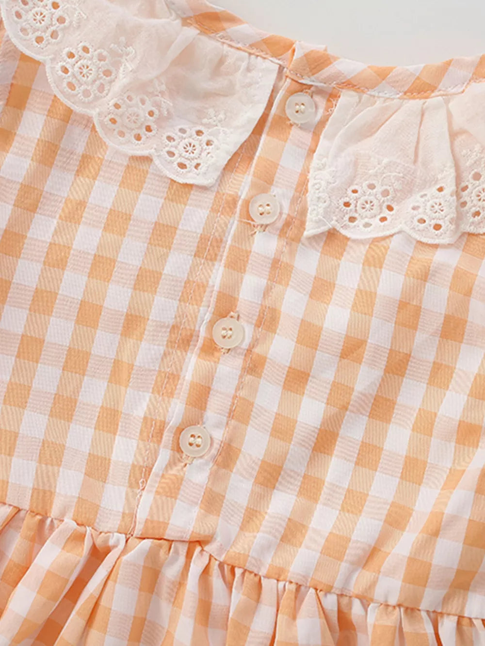 Baby dress with orange gingham pattern, lace collar, and ruffle hem.
