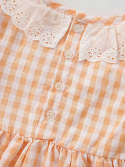 Baby dress with orange gingham pattern, lace collar, and ruffle hem.
