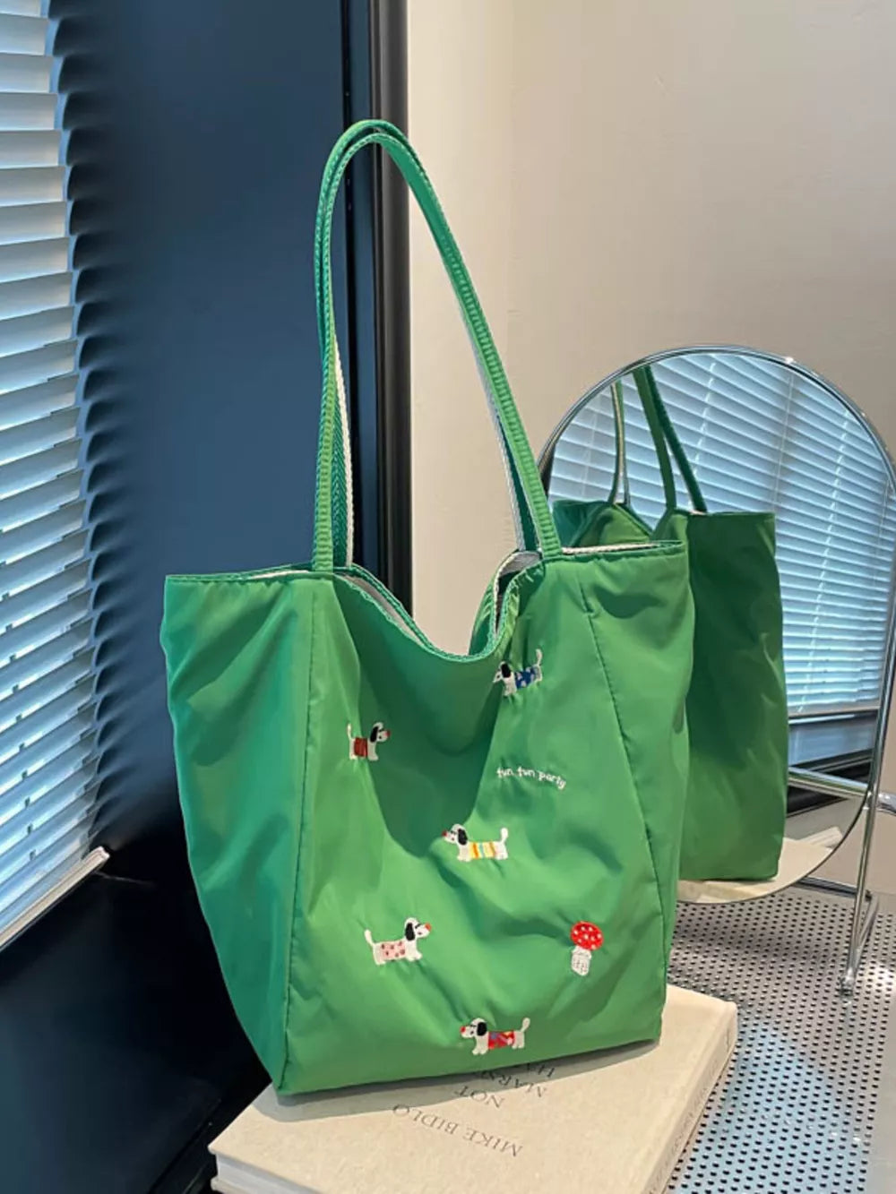 Green shoulder bag with embroidered dachshunds and a mushroom detail.