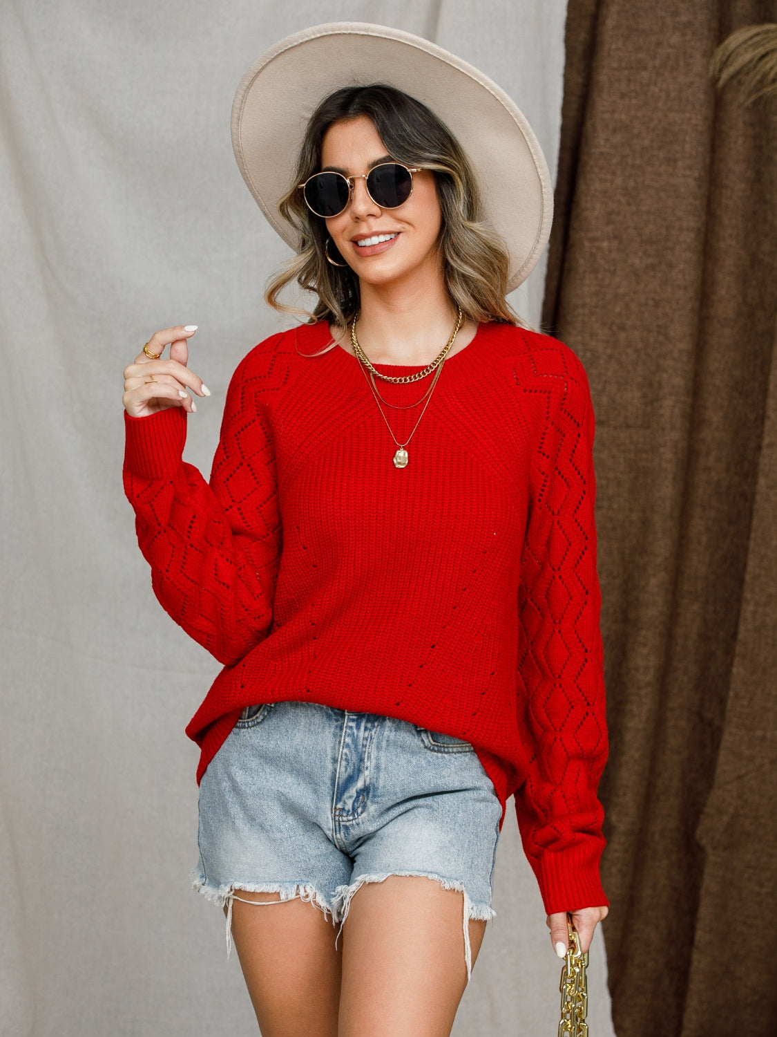 Diamond-cut raglan knit sweater in deep red with open knit diamond pattern on sleeves.