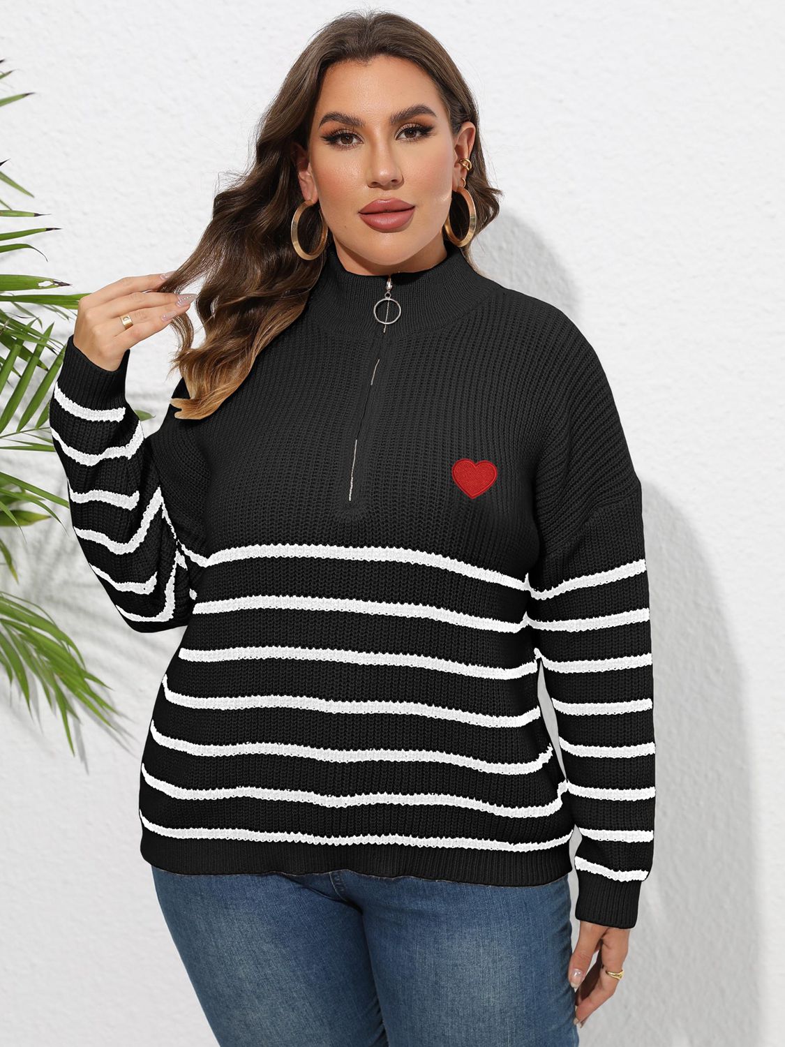 Black ribbed knit sweater with white stripes, red heart appliqué, and quarter zip band collar.